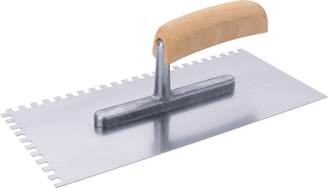 Pajarito_Dummy_Spreading trowel wooden handle notched_036580_ 089371_089372_089373_036584_089374_036592_2021-2 Truelle rectangulaire à dents avec lame métallique polie et poignée en bois courbée ; un long côté présente des encoches carrées régulières et la fixation métallique est estampillée « Made in Germany ».