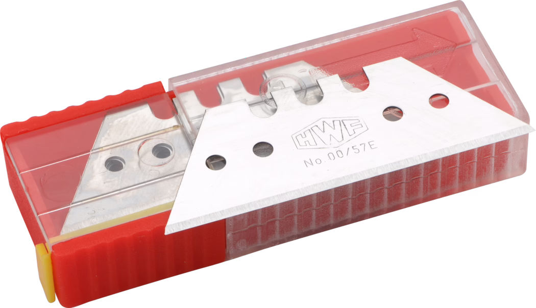 Gros plan d'un paquet de lames de rechange pour cutter dans un distributeur rectangulaire en plastique rouge à couvercle transparent. Une lame métallique argentée estampillée 'HWF No.00/57E' repose partiellement à l'extérieur du contenant, montrant son tranchant biseauté et ses trous de fixation circulaires. La base rouge présente une surface texturée pour la préhension et un bouchon jaune à l'extrémité. Le couvercle en plastique transparent laisse apercevoir d'autres lames empilées à l'intérieur. Un éclairage studio met en valeur la brillance métallique et le fil fin.