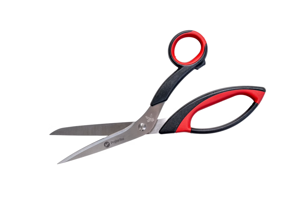 Pajarito_Dummy_Textile scissors_089416_2021-02 Une paire de ciseaux en acier inoxydable avec des poignées ergonomiques en plastique noir et rouge, partiellement ouverts sur fond blanc ; les lames fines et pointues portent la marque « pajarito » sur une lame.