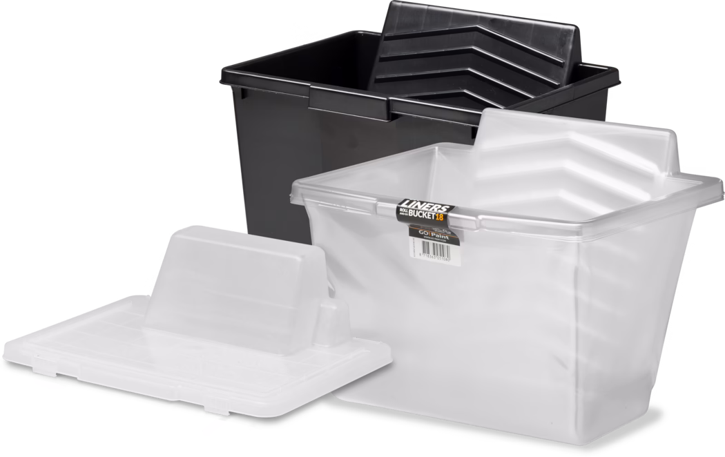 A group of plastic paint trays and liners: a large black rectangular plastic paint bucket in the background and two translucent white plastic liners in the foreground, one fitted partially inside the black bucket and another lying flat with a ribbed spill and roller rest. The liners feature angled ribbed grooves for rolling, a rectangular pour lip, and one has a small product label that reads 'LINERS BUCKET 18'. Bright studio lighting on a white background highlights the glossy texture and molded details of the plastic parts.