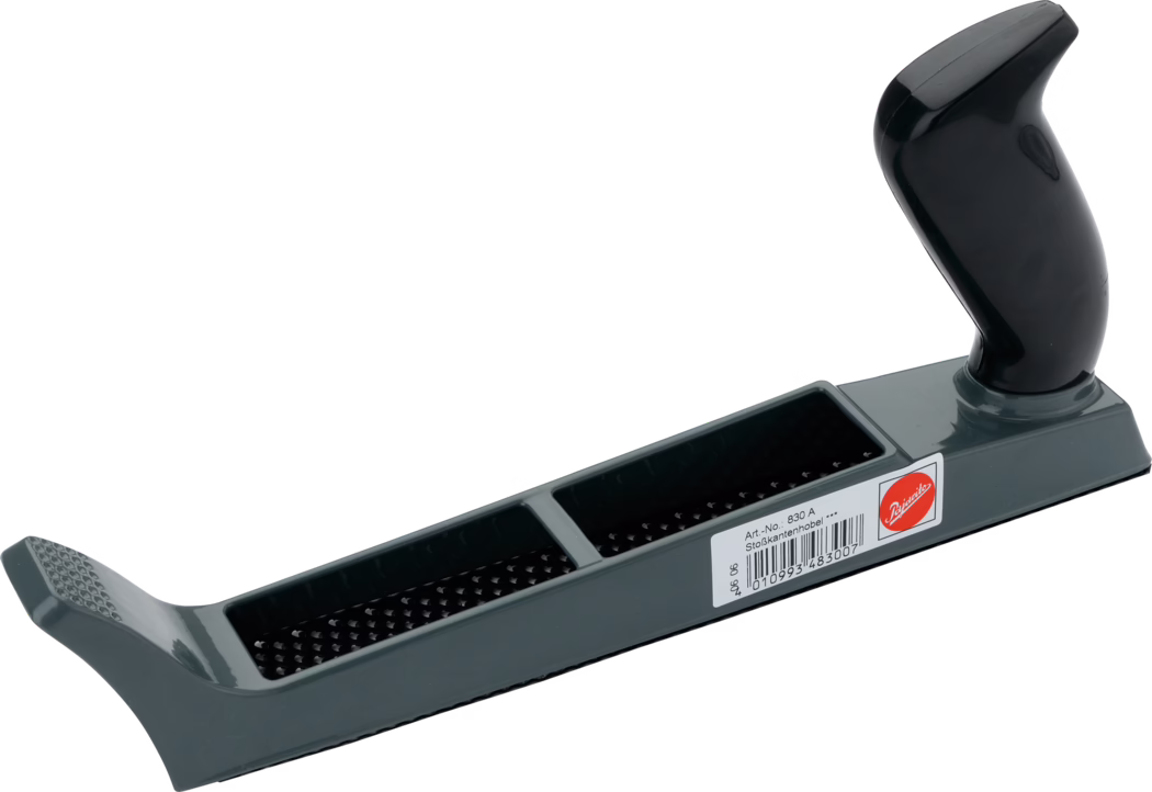 Photographie d'une râpe manuelle (rabot-rasp) avec un corps long et plat en plastique gris et une poignée pistolet ergonomique brillante noire fixée à l'arrière. La semelle de l'outil comporte deux cavités rectangulaires équipées de lames râpeuses perforées à dents serrées (type surform), visibles comme des rangées de petites dents pyramidales saillantes; l'avant présente une surface texturée pour le pouce. Un autocollant blanc avec un code-barres et un petit texte imprimé, ainsi qu'un logo circulaire rouge, sont apposés sur le côté. La râpe est positionnée en diagonale sur un fond blanc, photographiée légèrement en contre-plongée pour mettre en valeur la longueur, les surfaces de coupe texturées et la poignée moulée; elle sert à façonner, niveler et enlever de la matière sur le bois, le plâtre ou d'autres matériaux tendres.