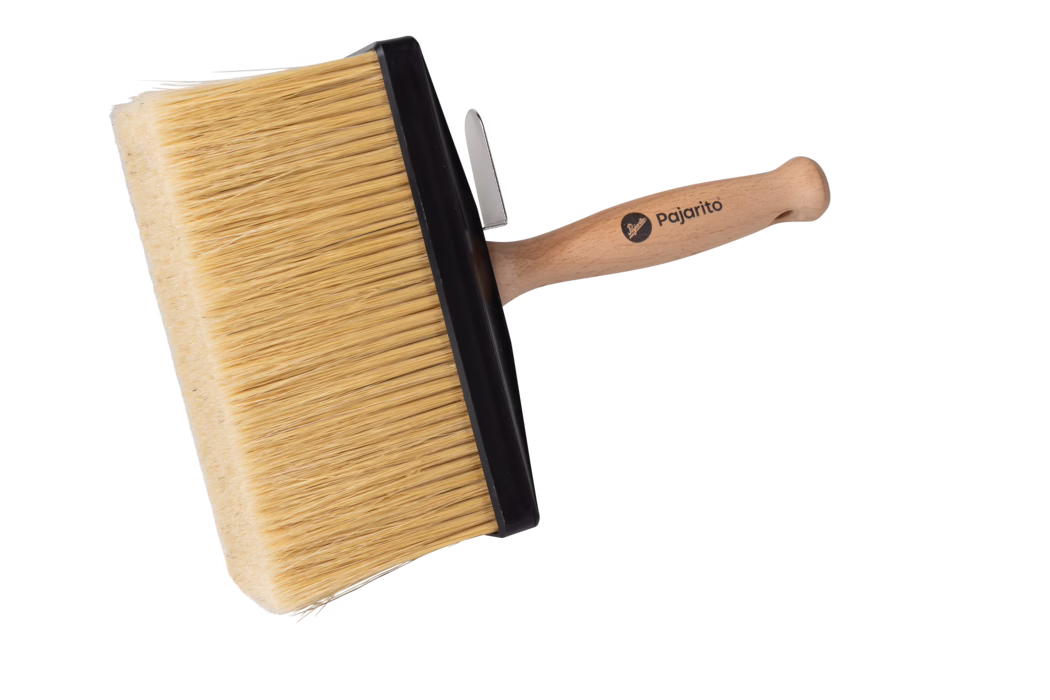 Grande brosse rectangulaire avec une large tête et des poils denses de couleur naturelle maintenus par une large collerette en plastique noir. Le manche ergonomique en bois clair porte le nom de marque imprimé « Pajarito » et une petite attache métallique est fixée près de la collerette. Photograhée sur fond blanc, l'image met en valeur la texture des poils, la finition lisse du bois et la vocation de la brosse pour couvrir de grandes surfaces comme les murs et les plafonds de manière uniforme.
