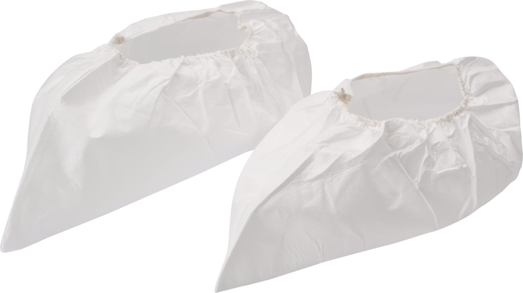 Pajarito_Dummy_Overshoes_034410_2021-02 Two disposable white shoe covers made from lightweight, slightly textured synthetic material are shown side by side on a white background. Each cover features an elasticized opening, a tapered toe shape and visible folds and seams, suggesting single-use protective footwear for cleanrooms, medical environments or painting and maintenance tasks; one cover is positioned slightly behind the other and soft studio shadows emphasize volume and form.