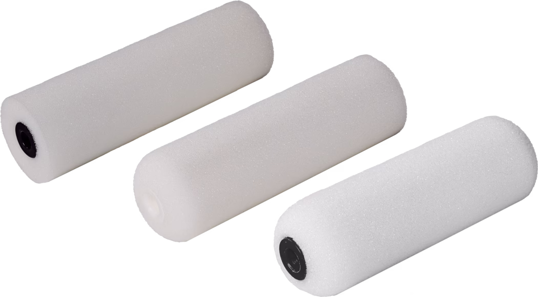 Trois manchons de rouleau en mousse blancs disposés en diagonale sur un fond blanc. Chaque manchon est cylindrique, avec une texture de mousse à pores fins ; deux présentent des embouts en plastique noirs et le troisième un embout blanc. Les rouleaux sont isolés sur l'image, adaptés aux petites tâches de peinture et de finition ; un éclairage doux et uniforme met en valeur la surface poreuse, la texture fine et les ombres subtiles.