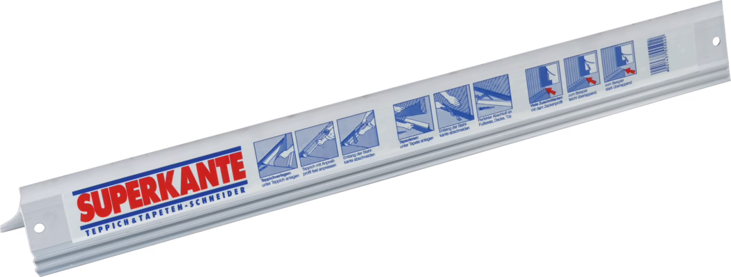 Profil long en plastique blanc portant la marque 'SUPERKANTE' en rouge et bleu et l'inscription 'Teppich & Tapeten-Schneider'. L'outil présente plusieurs pictogrammes bleus expliquant les étapes de découpe de moquette et de papier peint, possède des trous aux extrémités et est photographié en diagonale sur fond blanc.
