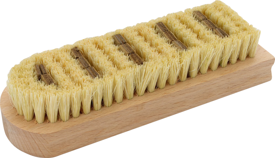 Gros plan d'une brosse rectangulaire en bois pour récurer, avec des poils naturels jaunâtres densément alignés en plusieurs rangées sur un bloc de bois lisse et clair ; de petites pièces brunes sont visibles entre les rangées de poils ; utilisée pour nettoyer et frotter des surfaces ; photographiée sur fond blanc.