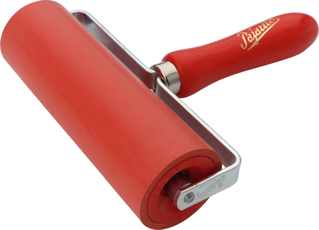 Gros plan d'un rouleau en caoutchouc rouge utilisé pour l'impression et pour lisser des surfaces. Le cylindre en caoutchouc rouge est monté dans une armature métallique en U avec un manche en bois tourné peint en rouge et orné d'une inscription dorée ; la texture du caoutchouc et la brillance du métal sont visibles sur fond blanc.