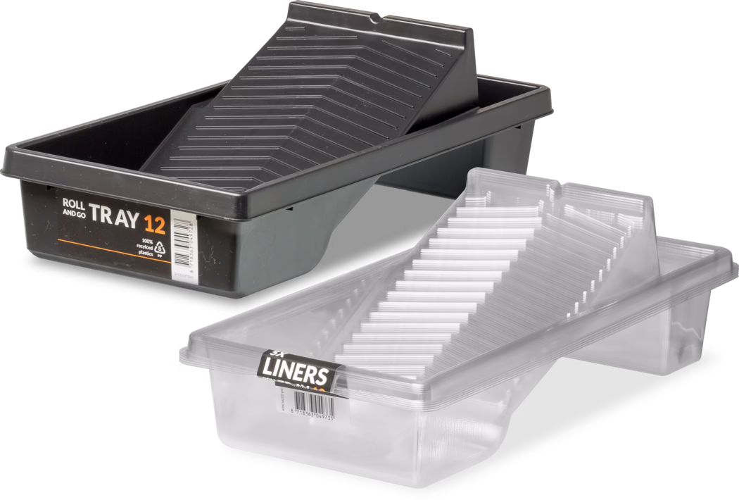 Product photograph of two plastic paint roller trays on a white background. A larger matte black tray labeled 'ROLL AND GO TRAY 12' sits at the rear, containing an angled, ribbed black insert designed to distribute paint evenly across a roller and drain excess paint back into the reservoir; the label shows a barcode and a '100% recycled plastics' mark. In front is a clear, semi‑transparent disposable liner shaped to fit the black tray, with pronounced parallel ribs and a stepped slope; several liners appear stacked together. The composition and soft studio lighting emphasize functional details—textured ramp, deep paint well, reinforced rim—and the image is suitable for retail product listing or instructional use.