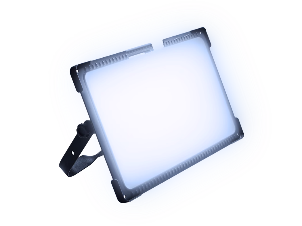 Gros plan d'un panneau LED professionnel incliné, émettant une lumière blanche froide et intense. Le châssis en aluminium et les équerres de protection aux angles sont visibles, ainsi que des entrées d'aération sur le bord supérieur et un support de fixation noir réglable avec une molette. Composition très lumineuse sur fond blanc avec une légère teinte bleutée mettant en valeur les arêtes nettes, les surfaces métalliques texturées et le design industriel.